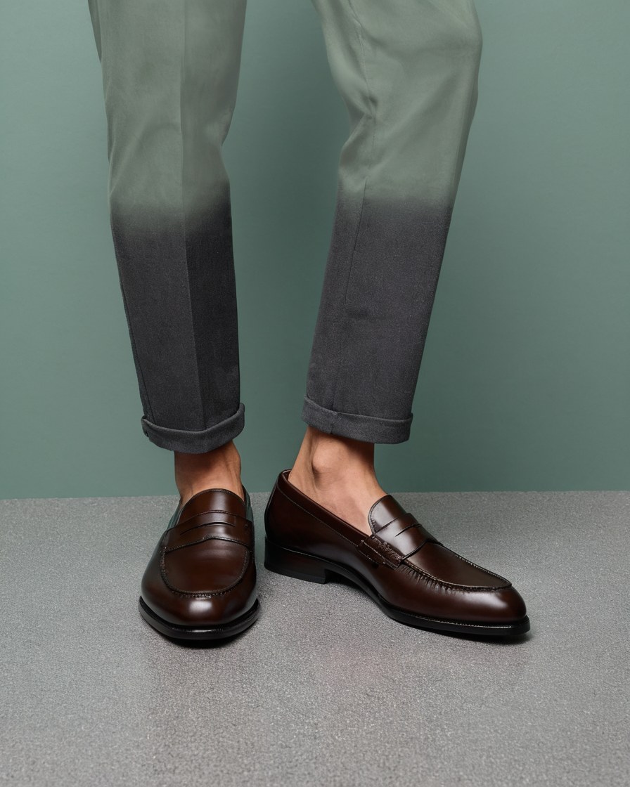 Mocasines de piel café con pantalón oscuro sobre piso claro