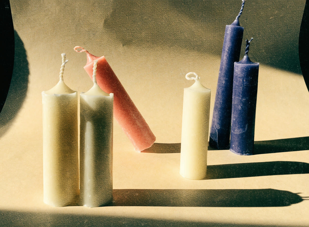 Velas de pilar en crema, coral e índigo con sombras largas