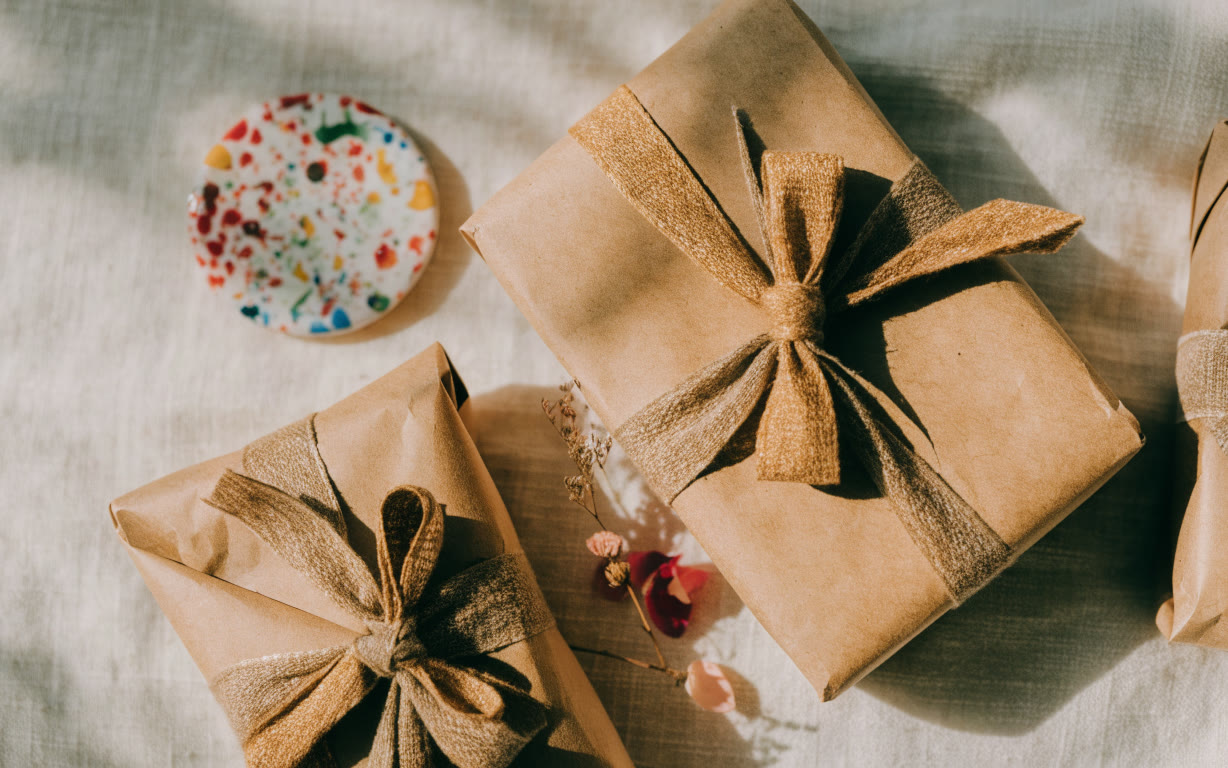 Regalos envueltos en papel kraft con listón de algodón y una ficha de cerámica