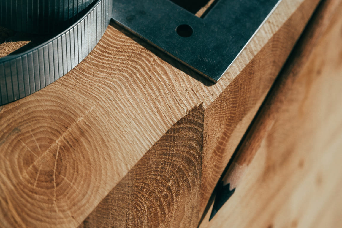 Escuadra y cinta métrica junto a una pieza de madera cortada