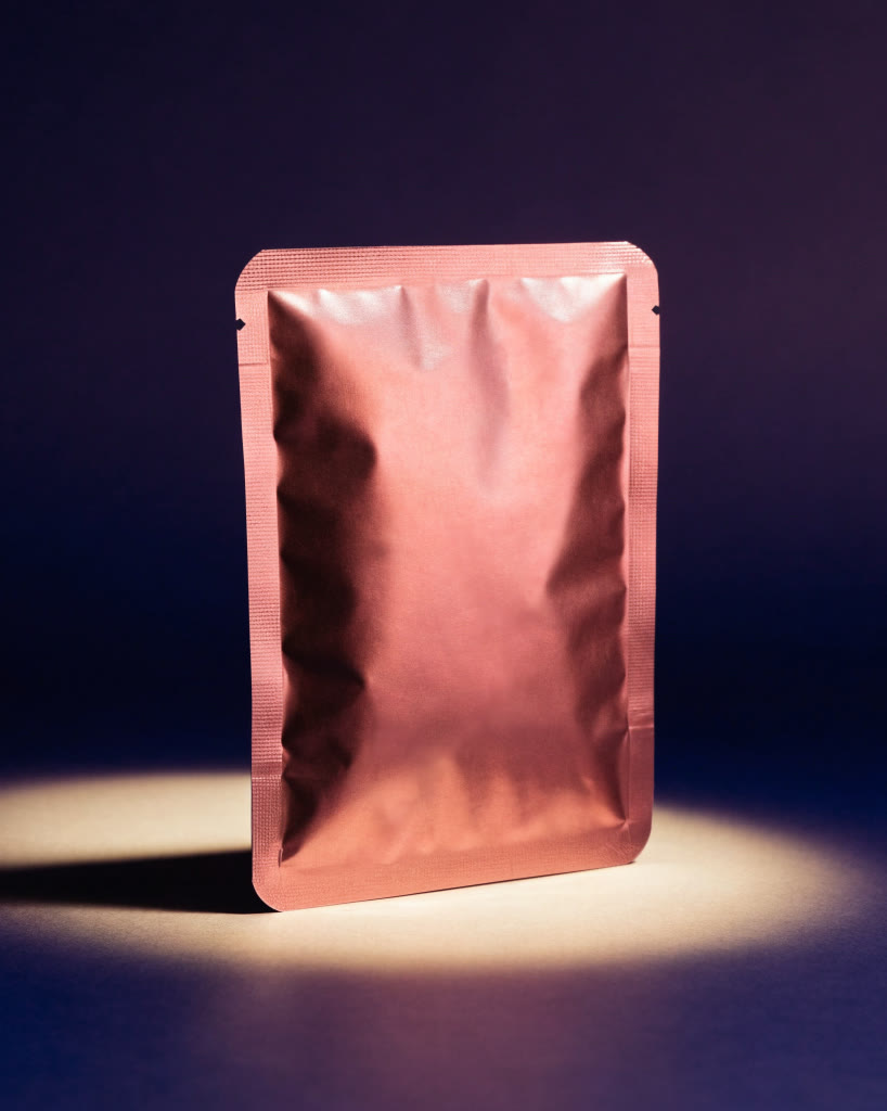 Sobre de cosmética coreana color coral bajo un haz de luz