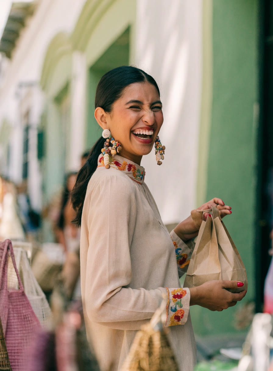 Mujer sonriente con aretes de chaquira y blusa bordada