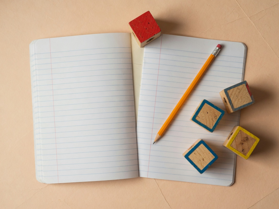 Cuaderno de rayas en blanco, un lápiz y cubos de letras sobre papel cálido