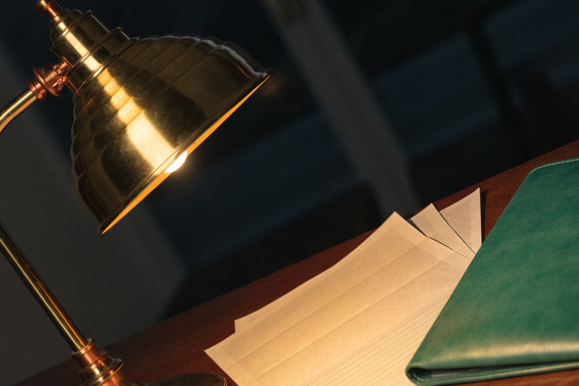 Lámpara de escritorio sobre papelería y carpeta de piel verde