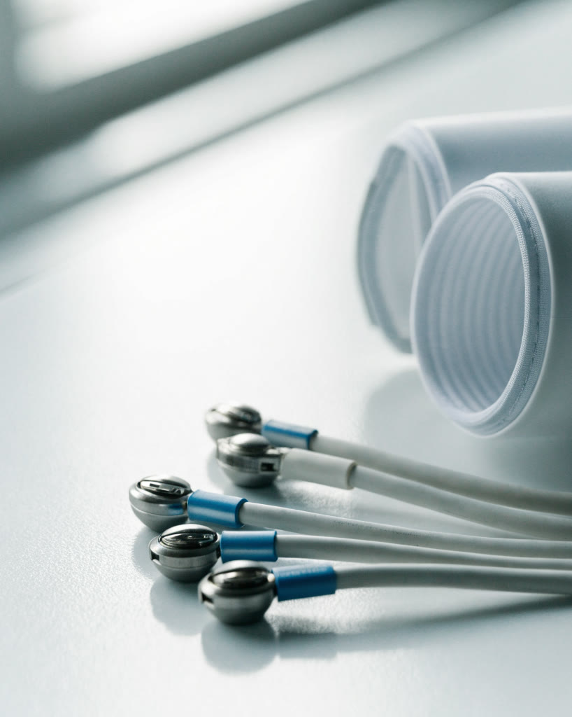 Cables y electrodos de electrocardiograma sobre una superficie clínica