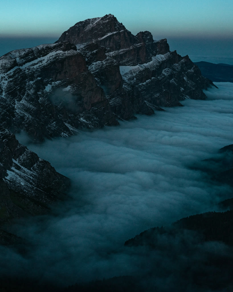 Cresta de montaña al anochecer sobre un mar de nubes