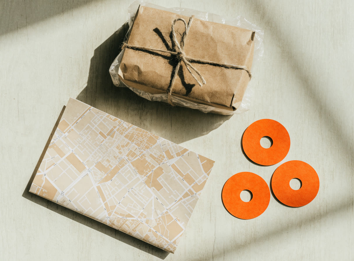 Paquete de papel kraft junto a un mapa doblado y fichas de ubicación